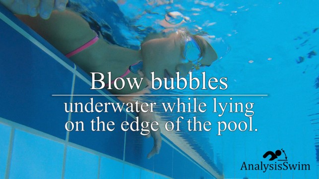 Blow Bubbles underwater while lying on the edge of the pool